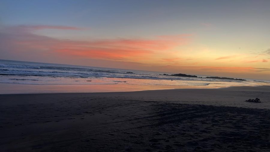 Playa de El Tránsito al anochecer con el cielo rosado.