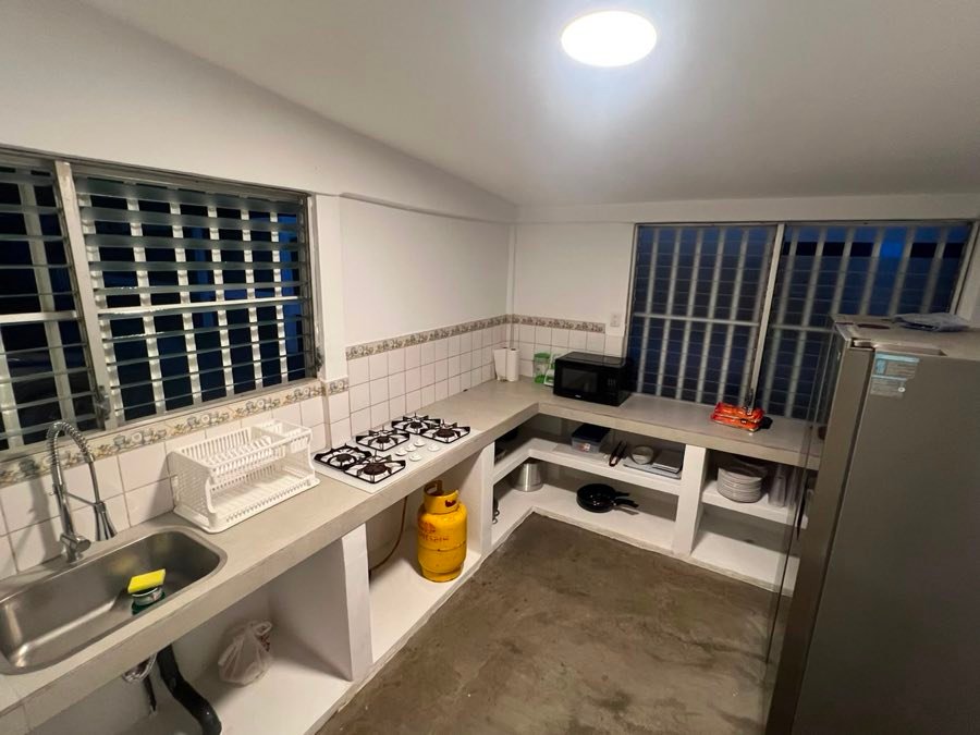 Cocina de la casa con estufa, refrigeradora, microondas y área de lavado.