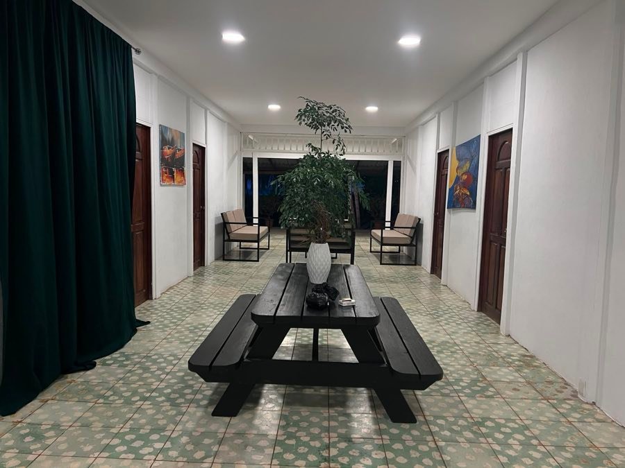 Comedor común con mesa larga de madera y piso de mosaico.